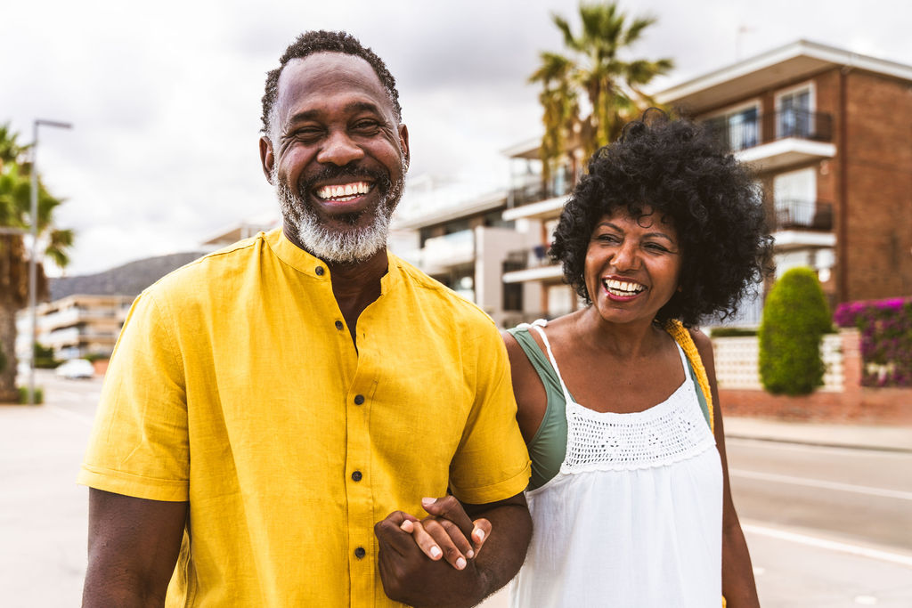 A couple walking hand in hand down a sunny suburban street