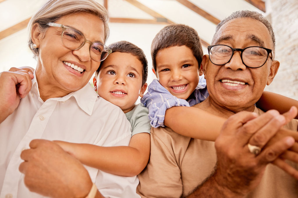 Grandparents smiling with their two grandchildren at home
