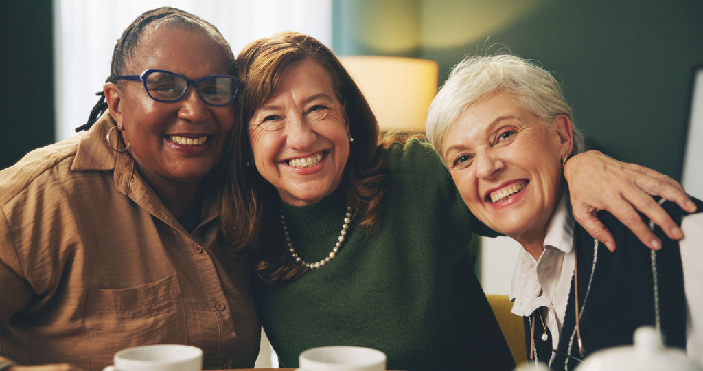 Three friends laughing together over coffee